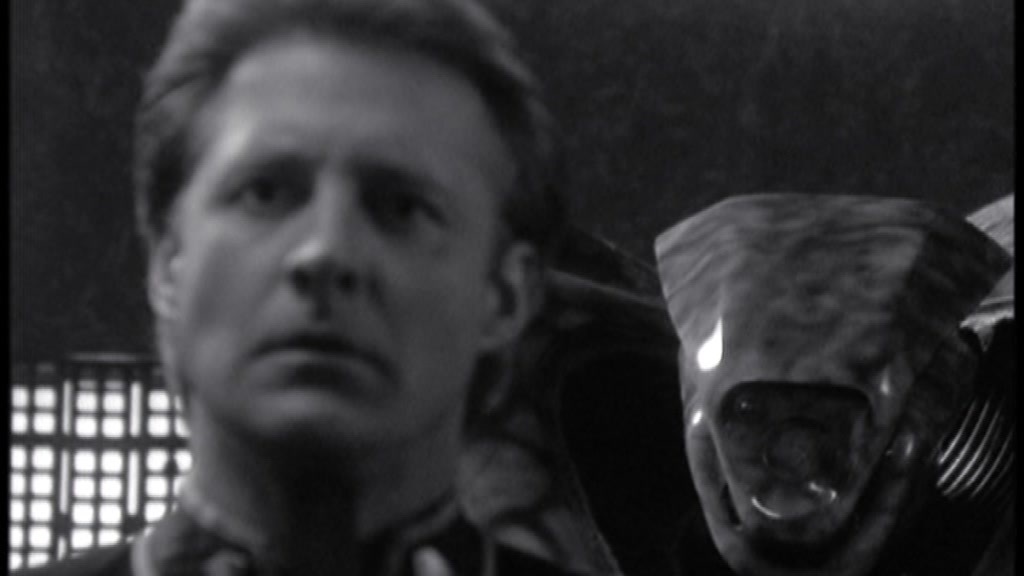 Black-and-white screencap from Babylon 5 featuring Captain Sheridan being spoken to by a piece of an ancient guardian species inside his head.